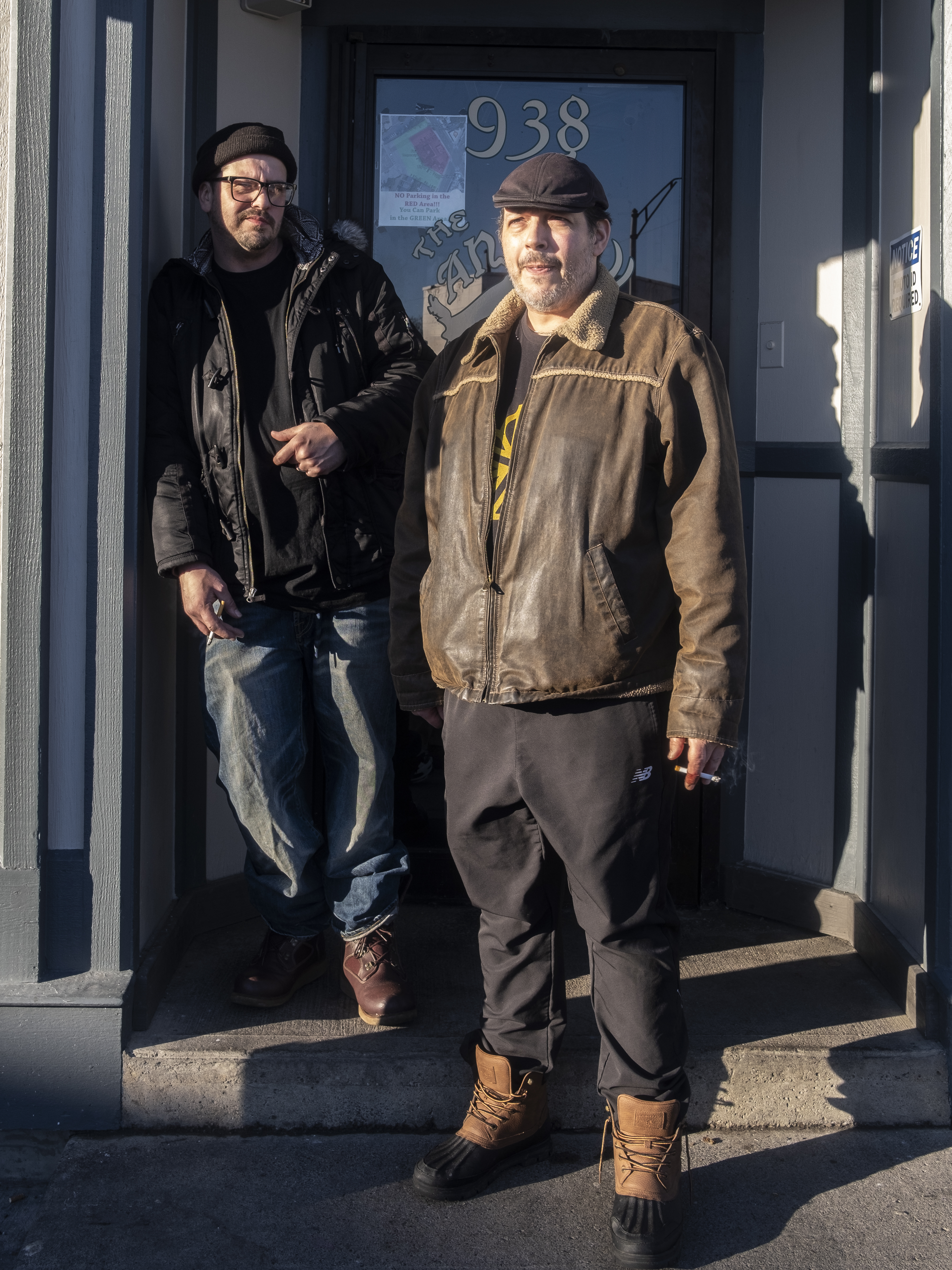 The Angry Goat proprietors smoke cigarettes on front steps of establishment